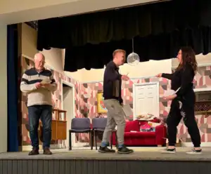 Actors practicing dialogue during a theatre rehearsal on stage.